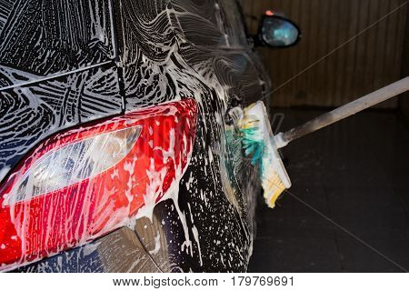 black car with white foam in the carwash
