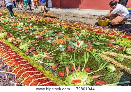 Antigua, Guatemala - March 26 2017: Locals make procession carpet of vegetables during Lent in colonial town with most famous Holy Week celebrations in Latin America.