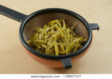Canned French cut green beans draining in strainer