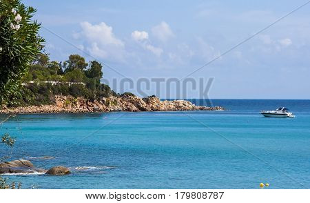 Scenery view on Italian island Sardinia sea shore beach rock coast and anchored boat in Arbatax sardegna