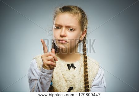 displeased and contemptuous girl with threatens finger isolated on gray background