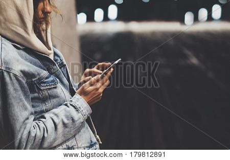 Girl pointing finger on screen smartphone on background illumination bokeh color light in night atmospheric city bridge hipster using in female hands and texting mobile phone mockup glitter street lifestyle