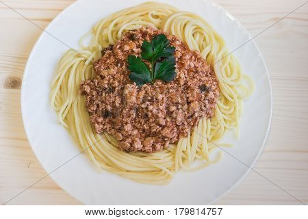 hot spaghetti with red meat sauce on big white plate on a wood table view from above. Health food concept