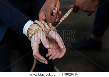 Impossible to get away. Nice unhappy stressed man sitting on the floor and having his hands tied while being kidnapped