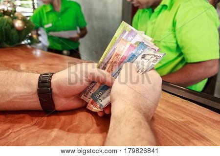 Closeup of male hands of tourist counting Sri Lankan money at conter