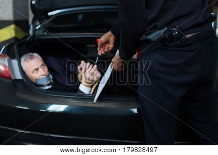 Take it and sign the document. Nice serious male criminal looking at his victim and giving him a pen while forcing him to sign the document