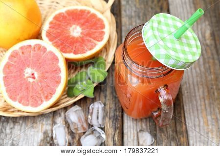Grapefruit juice in two glass mugs and grapefruit halves in wicker basket