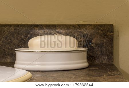 Bar Of White Soap In Dish Sitting On Dark Washbasin