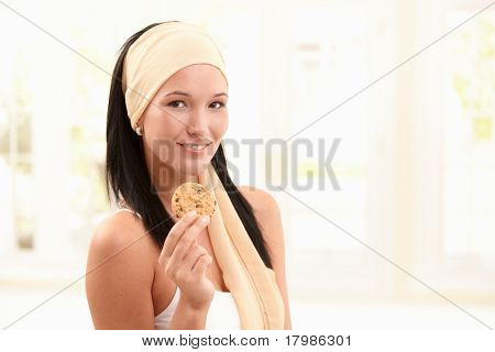 Portræt af glade attraktiv kvinde i forfang holder op cookie, smilende på kamera, copyspace.
