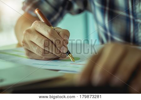 hand hold fountain pen pointing stock maket chart in office. vintage effect.