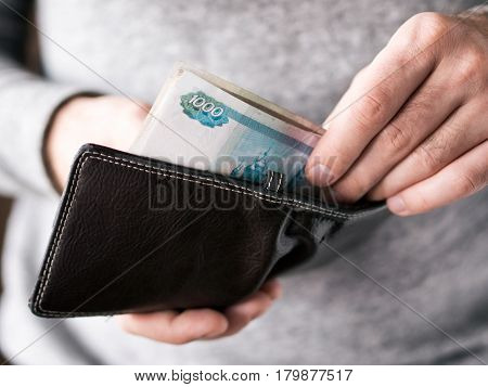 Hands take out russian rubles from wallet. Closeup on a man's hands as he is getting a banknote out of his wallet