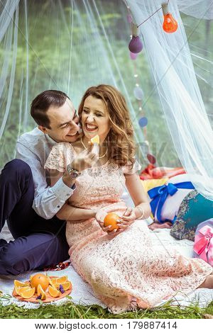 Smiling man and woman sitting on the ground and holdind a piece of orange in Lviv, Ukraine.