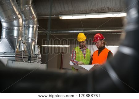 Workers making final touches to HVAC system. HVAC system stands for heating, ventilation and air conditioning technology. Team work, HVAC, indoor environmental comfort concept photo.