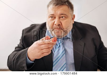 Engulfing hundreds of calories. Immoderate tired stressed employee eating junk food while having a lunch break and not taking care of his health
