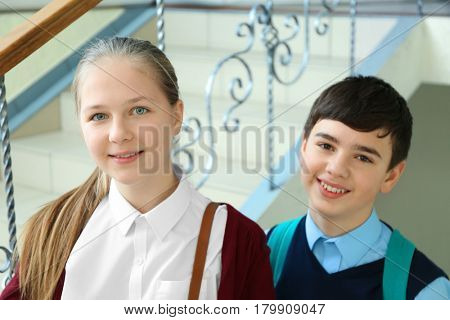 Cute boy and girl in school uniform standing on stairs