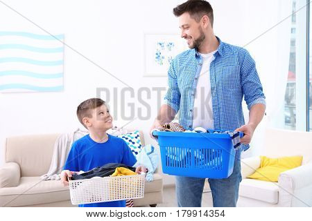 Dad and son with baskets of dirty clothes at home