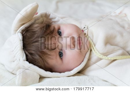 Little Beautiful Baby In A Funny Costume With Ears Lying On His Back.