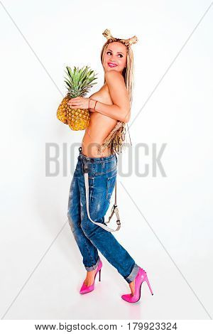 attractive young topless blonde woman with Piercing and african plaits with pineapples in her hands on colorful background
