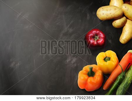 Young spring vegetables on black chalkboard from above food