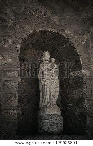 Statue of virgin Mary with stoned background. White stone statue of Saint Mary. Virgin Mary and baby Jesus. Jesus Christ and saint Mary sculpture.