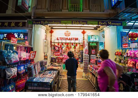 SINGAPORE - MARCH 5: Shoppers walk through a Chinatown market at night on March 5 2015 in Singapore. The city state's ethnic Chinese began settling in Chinatown circa 1820s.