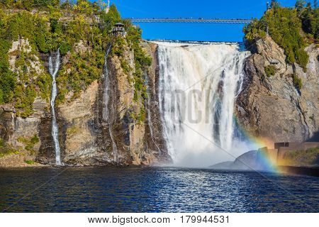 The magnificent rainbow plays in falls splashes. The blue lake and powerful waterfall Montmorency in Montmorency Falls Park, in Quebec. The concept of active and cultural tourism
