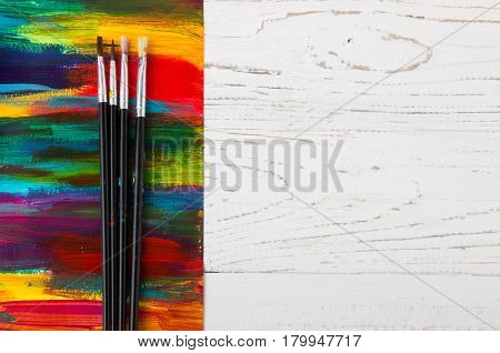 Artist's workshop.Items for children's creativity on a wooden background. Acrylic paint and brushes on white wooden background. Picture with copy space and for add text. some art stuff on wooden table
