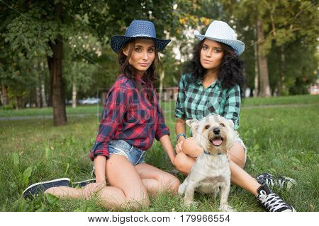 Two girls walking with his dog. cowboy hat and plaid shirt. Outdoodrs.