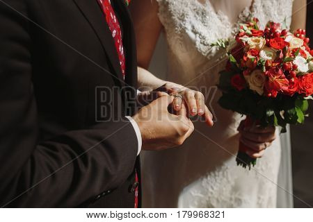 wedding ceremony at church. stylish groom and bride exchanging wedding rings and giving vows. spiritual sensual moment.