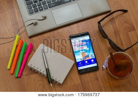 Nitra, Slovakia, april 3, 2017: Wizzair application in a mobile phone screen. Workplace with a laptop, an earphones, notepad, pen, tea, sunglasses and color markers on wooden background