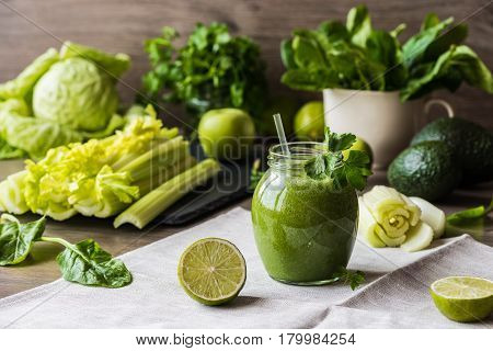 Detox diet. Green smoothie with different vegetables on wooden background.