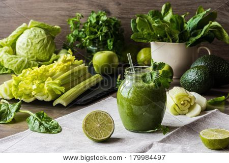 Detox diet. Green smoothie with different vegetables on wooden background.