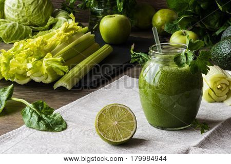 Detox diet. Green smoothie with different vegetables on wooden background.