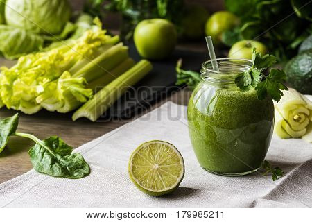 Detox diet. Green smoothie with different vegetables on wooden background.