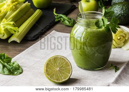Detox diet. Green smoothie with different vegetables on wooden background.