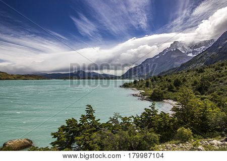panorama of shore of blue lake and sky with windy clouds in patagonia at daylight