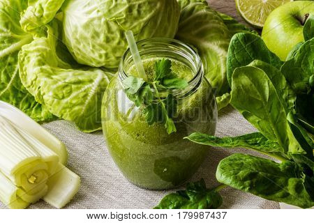 Detox diet. Green smoothie with different vegetables on wooden background.