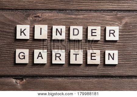 Alphabet letters on wooden pieces collected to word kinder garten