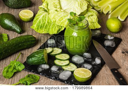 Detox diet. Green smoothie with different vegetables on wooden background.