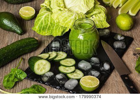 Detox diet. Green smoothie with different vegetables on wooden background.