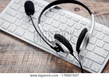 operator headset and computer keyboard on workdesk for call center concept on wooden background