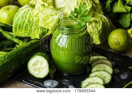 Detox diet. Green smoothie with different vegetables on wooden background.