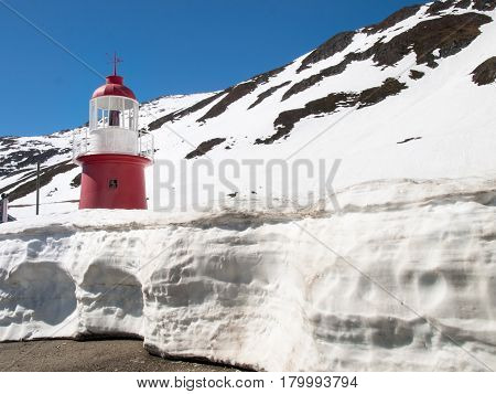 Andermatt Switzerland - May 14 2015: Lighthouse Oberalppass. The lighthouse is surrounded by snow and is illuminated by the sun during a beautiful day on the day of the Feast of the Ascension