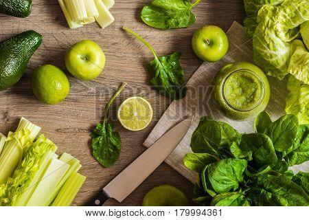 Detox diet. Green smoothie with different vegetables on wooden background.