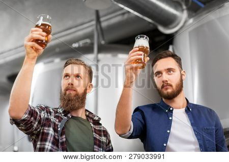 alcohol production, manufacture, business and people concept - men drinking and testing craft beer at brewery