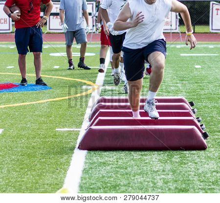 A High School Football Player Is Running Over Red Barriers That Are Placed On The Ground During A Pr