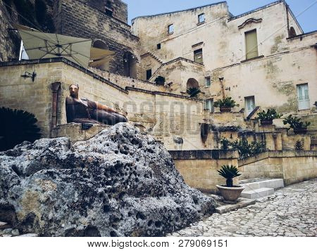 Beautiful Statue Of The Lying Woman La Matrona On The Background Of The Ancient Buildings Of Matera,