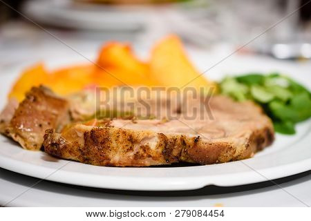 Delicious Pork Steak With Golden Baked Potatoes And Salad On White Plate