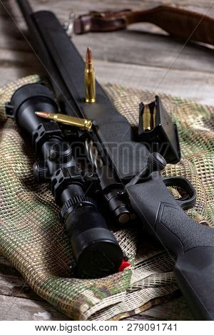 The Ammo With Black Bolt Action Rifle And Scope On The Multicam Background. Close Up.