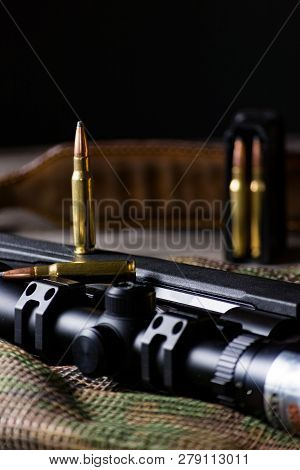 The Ammo With Black Bolt Action Rifle And Scope On The Multicam Background. Close Up.